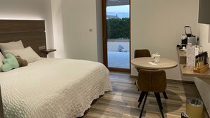 Habitación de hotel con cama, mesa redonda con sillas, una pequeña cocina y vista a través de una puerta.