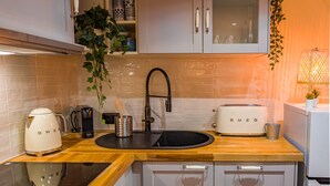 A modern kitchen with a wooden countertop, a black sink, a white toaster, and a coffee maker. - Cosy new apartment (Nice)