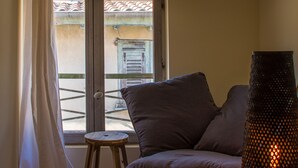 A cozy living room with a sofa, a small stool, and a lamp. - Cosy new apartment (Nice)
