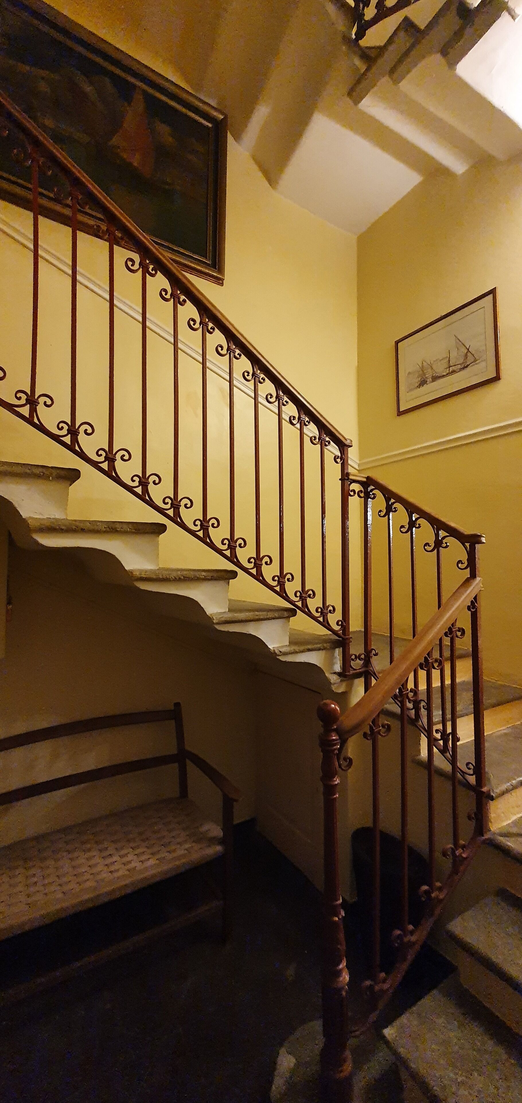 Eine Treppe mit aufwendiger Metallgeländerung und Holzhandläufen, die zu einer oberen Etage führt.