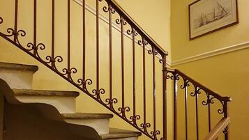 Eine Treppe mit aufwendiger Metallgeländerung und Holzhandläufen, die zu einer oberen Etage führt.