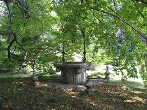 Une fontaine en pierre, entourée d’arbres, dans un parc.
