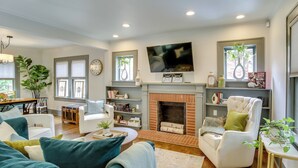 A modern living room with a fireplace, comfortable seating, and a flat-screen TV. - Renovated Lubbock Home - Walk to Texas Tech! (Lubbock)