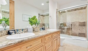 Une salle de bain moderne avec deux lavabos, un grand miroir, une douche avec des portes en verre et des toilettes.