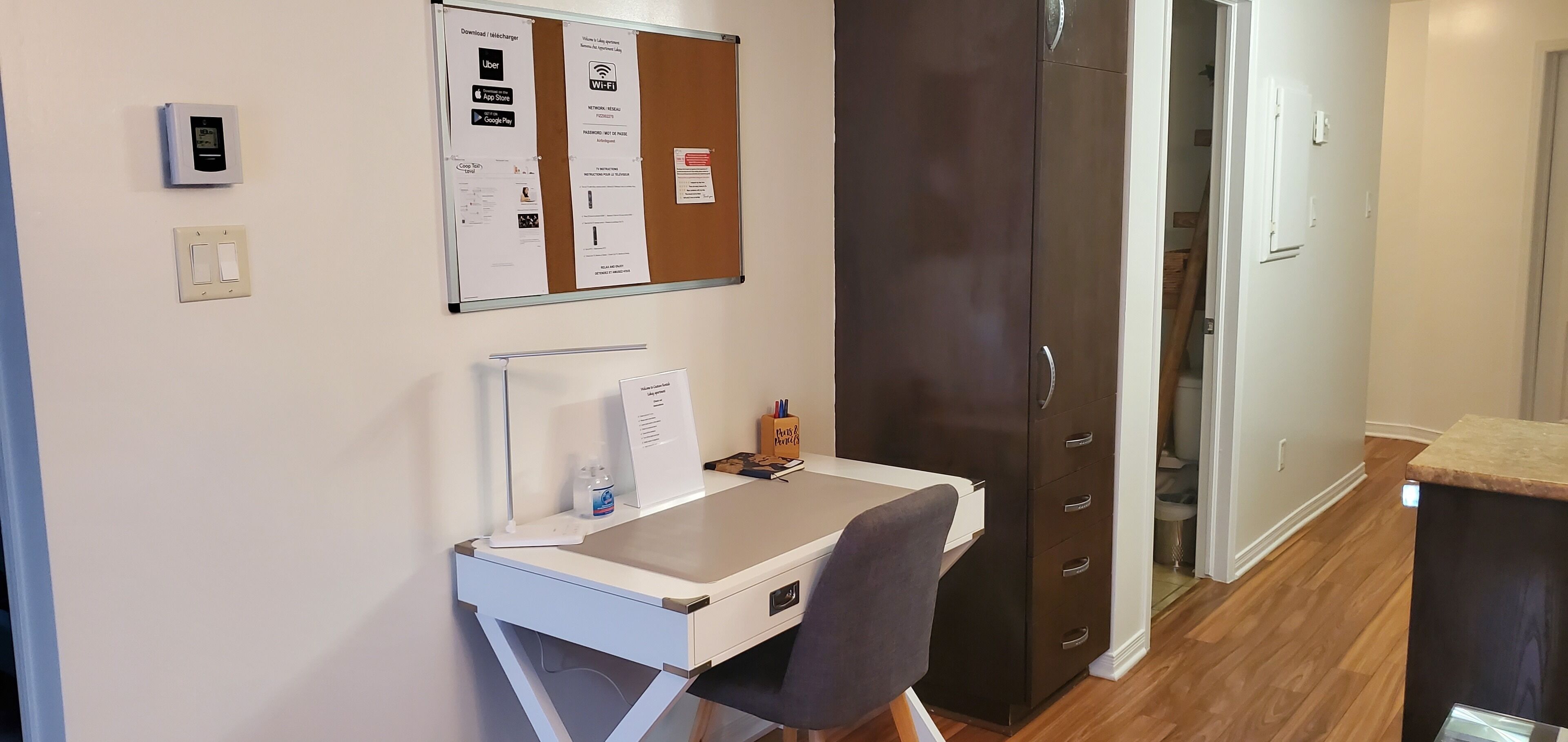 Habitació petita amb escriptori, cadira i un tablix amb diferents avisos.
