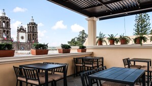Un patio al aire libre con mesas y sillas, con vistas a una iglesia histórica y un cielo despejado.