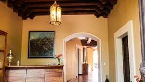 Un área de recepción con un mostrador de madera, un cuadro enmarcado y una escalera que sube a otro nivel.