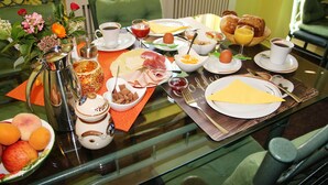 Una mesa de desayuno preparada con varios platos, incluyendo huevos, pan y frutas.