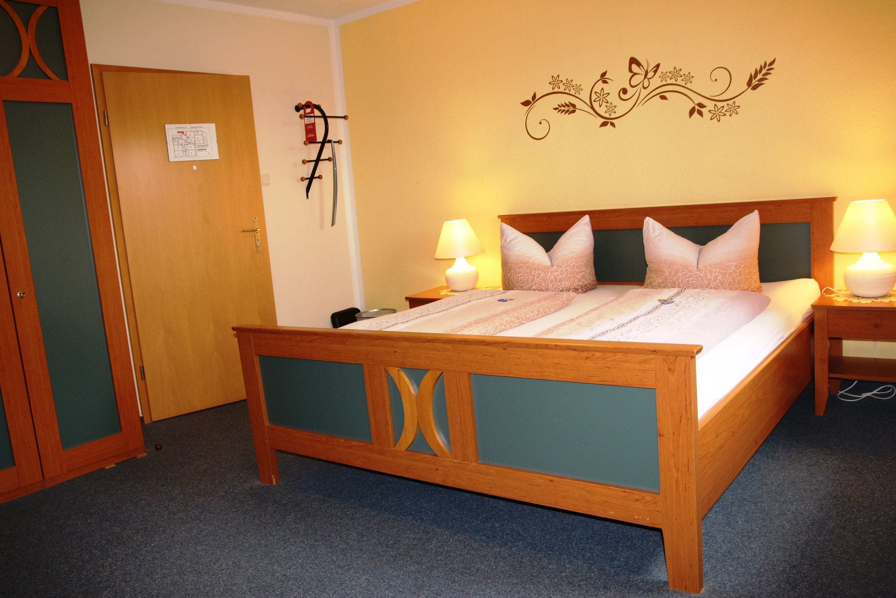 A wooden bed with a headboard, two bedside tables with lamps, and a wall decoration.