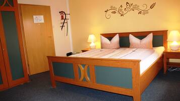 A wooden bed with a headboard, two bedside tables with lamps, and a wall decoration.