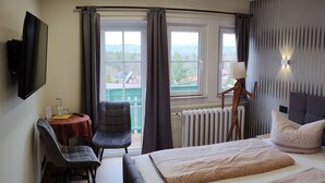Habitación de hotel con cama, escritorio, silla, lámpara y vistas al exterior.