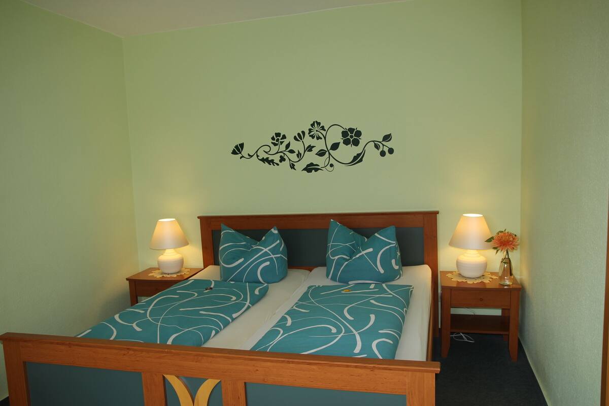 A bed with a floral wall decal, two bedside lamps, and matching pillows.