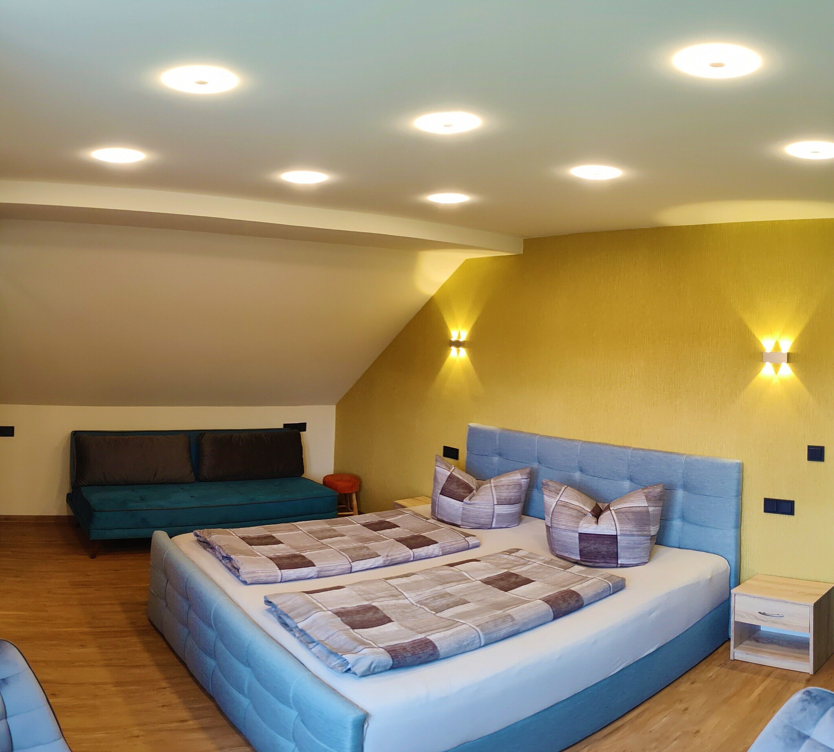 A bedroom with a large bed, a sofa, and a small stool.
