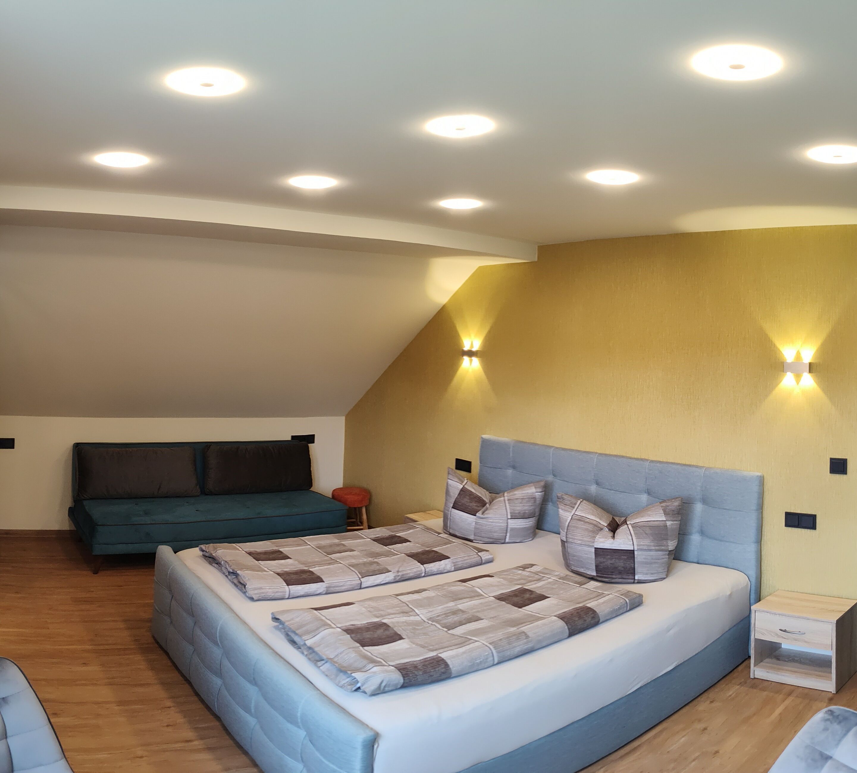 A bedroom with a large bed, a sofa, and a small stool.