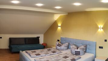 A bedroom with a large bed, a sofa, and a small stool.