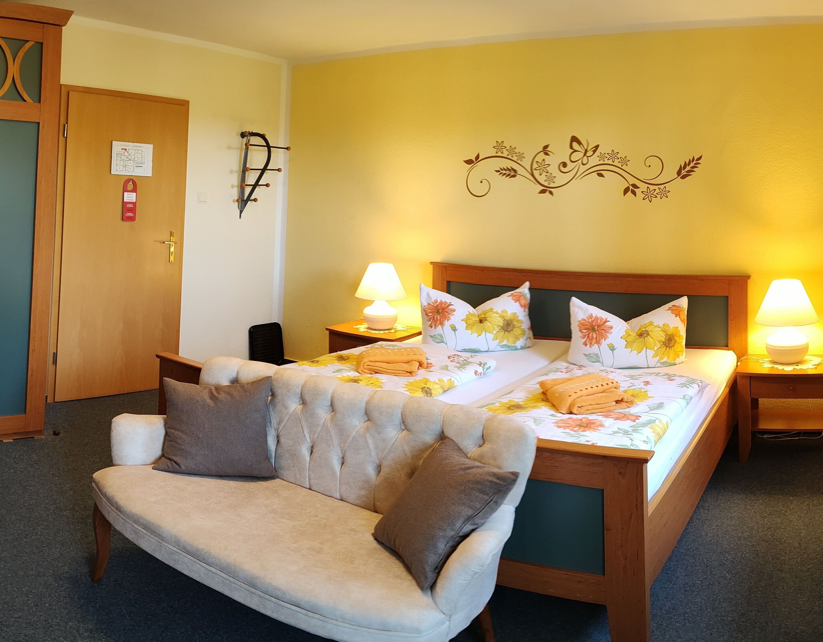 A hotel room with a bed, two bedside tables with lamps, a chair, and a wall map.