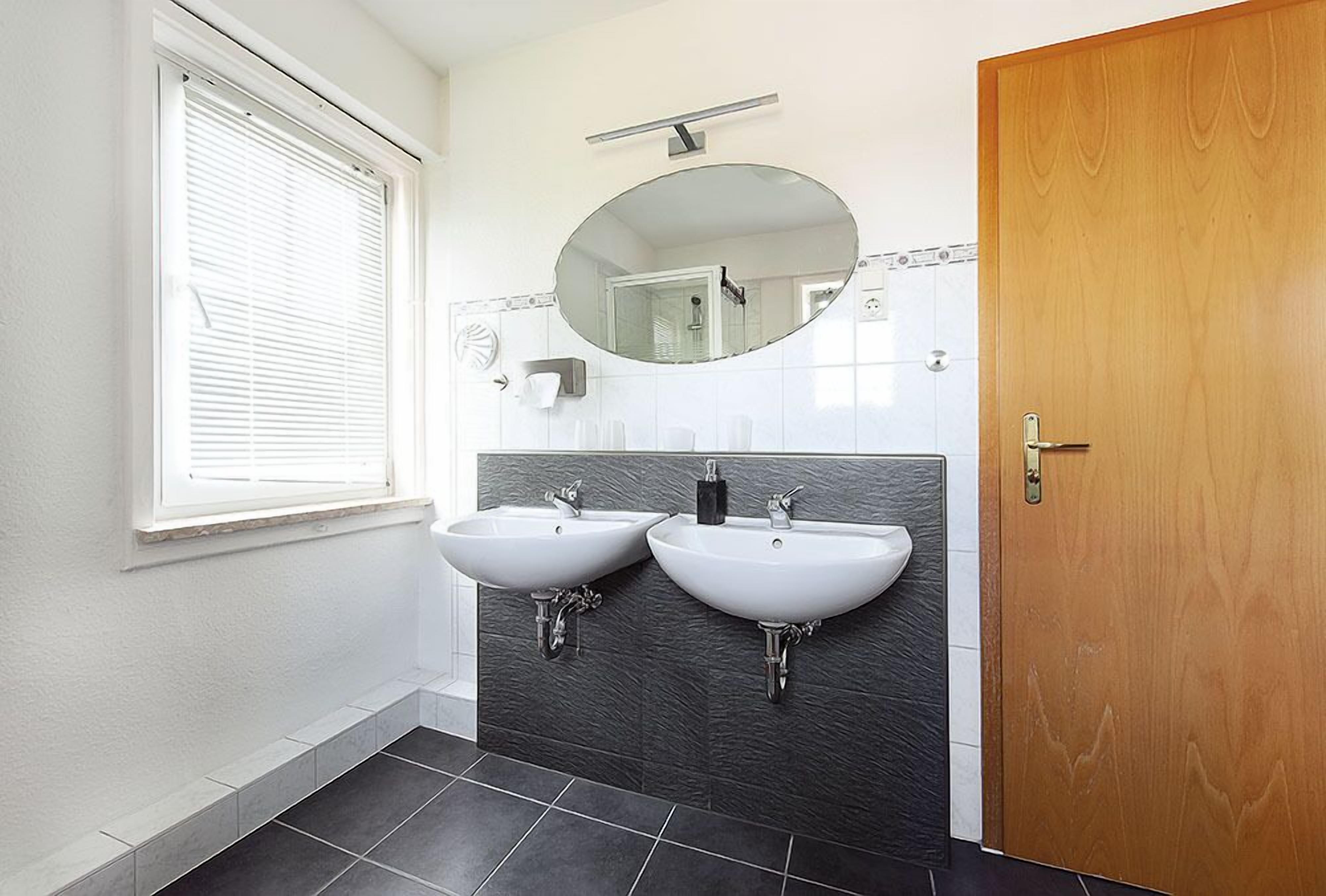 Un baño con dos lavamanos, un espejo y una puerta de madera.