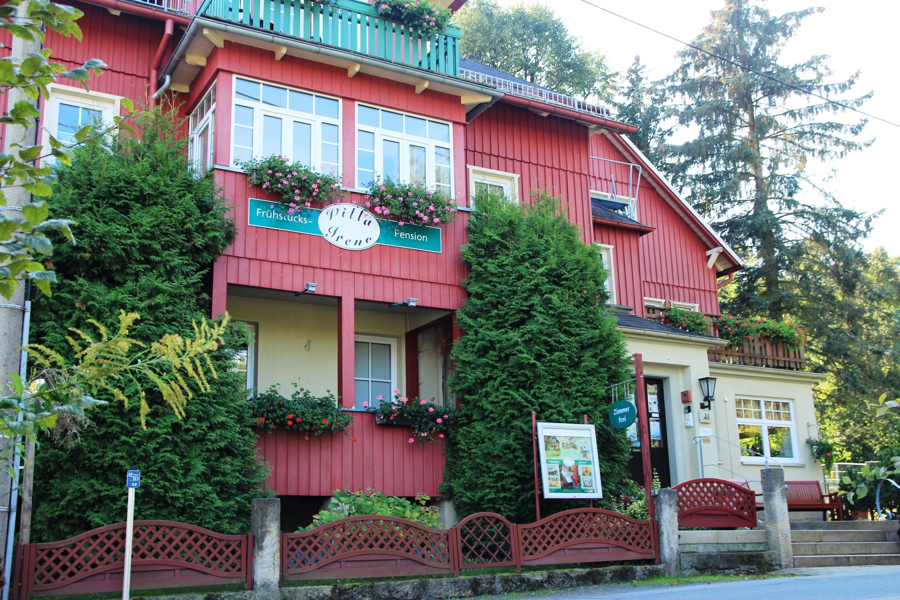 A red building with a sign reading "Villa Fröhlich Pension."