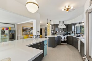 Enjoy cooking in this well-equipped kitchen with a large island, stainless steel appliances, and a stylish backsplash.