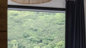 A room with a bed, a view of a lake, and a balcony with plants. - Amazing Waterfront Villa fully equipped w/ infinity pool (Moorea-Maiao)