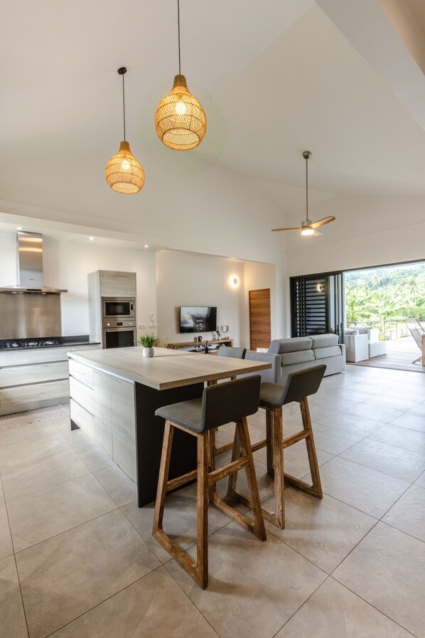 A modern kitchen with a central island, bar stools, and pendant lighting. - Amazing Waterfront Villa fully equipped w/ infinity pool (Moorea-Maiao)