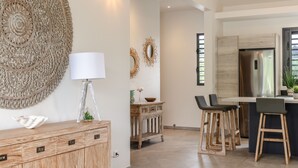 A modern kitchen with a wooden cabinet, bar stools, and a stainless steel refrigerator. - Amazing Waterfront Villa fully equipped w/ infinity pool (Moorea-Maiao)
