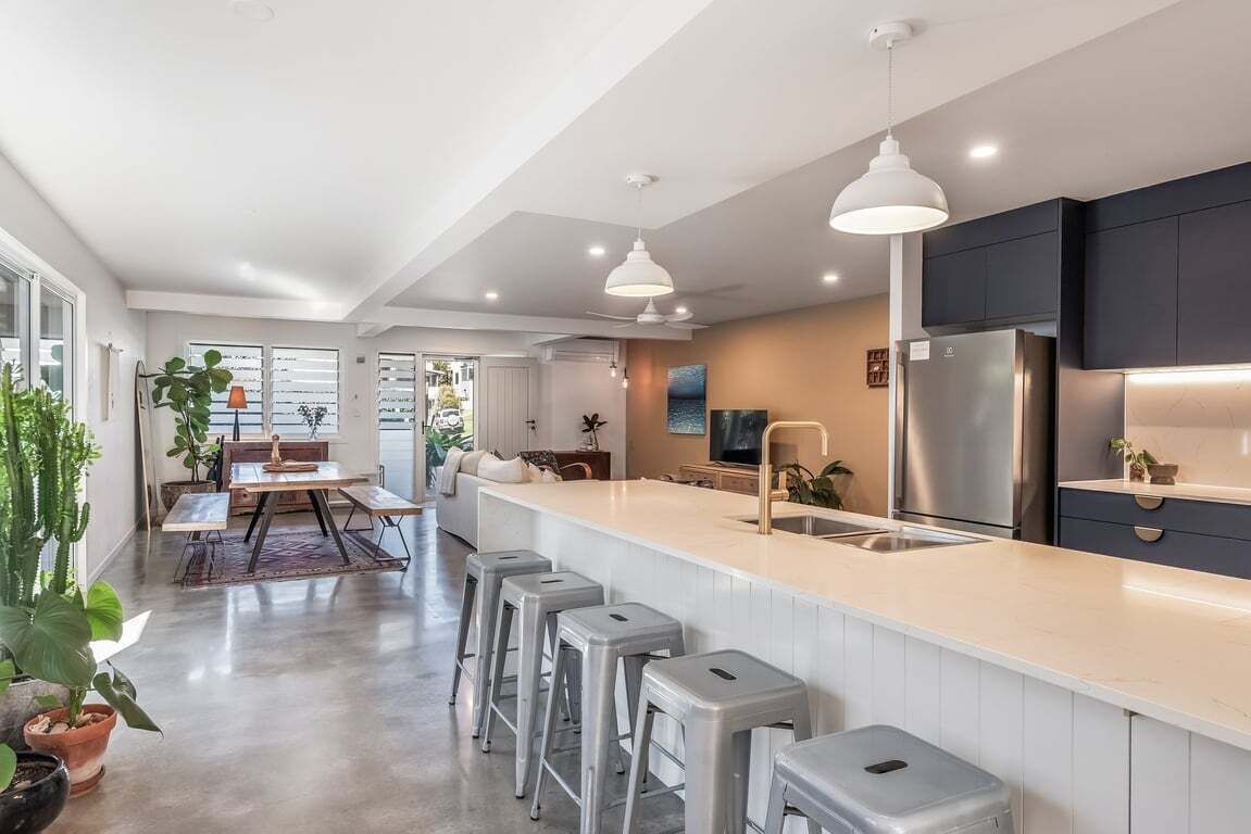 A modern kitchen with a central island, bar stools, and a stainless steel refrigerator.