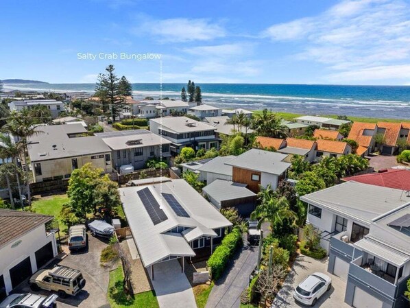 A coastal residential area with houses, a beach, and a clear sky.