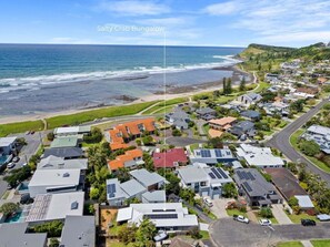 An aerial view of a coastal residential area with houses, a beach, and a road leading to a property labeled "Salty Crab Bungalow."