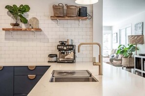 A modern kitchen with a built-in espresso machine, a sink, and a countertop.
