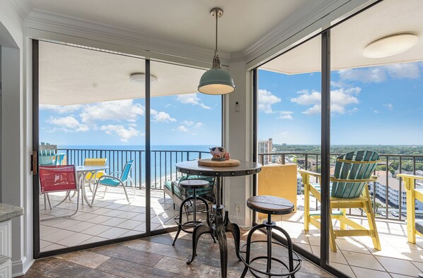 Ein Balkon mit Meerblick, ausgestattet mit einem runden Tisch, Stühlen und einer Pendelleuchte.
