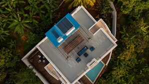 An aerial view of a modern house with a swimming pool, a sun terrace, and lush surrounding vegetation. - Banbou Terrace (Vieux Fort)
