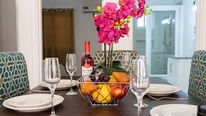 A dining table set with plates, wine glasses, a bottle of wine, and a fruit basket. - Banbou Terrace (Vieux Fort)