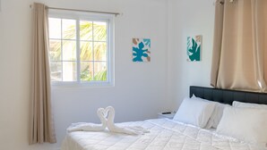 A hotel room with a bed, a window with curtains, and two wall art pieces. - Banbou Terrace (Vieux Fort)