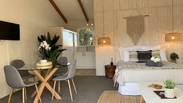 Ett modernt sovrum med en säng, sänglampor, ett sängbord och utsikt över naturen.