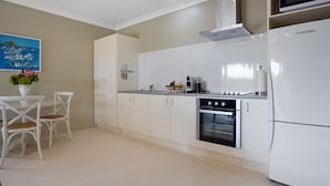 Une cuisine moderne avec des meubles blancs, un four encastré, un four à micro-ondes et un coin repas comprenant deux chaises et une table.