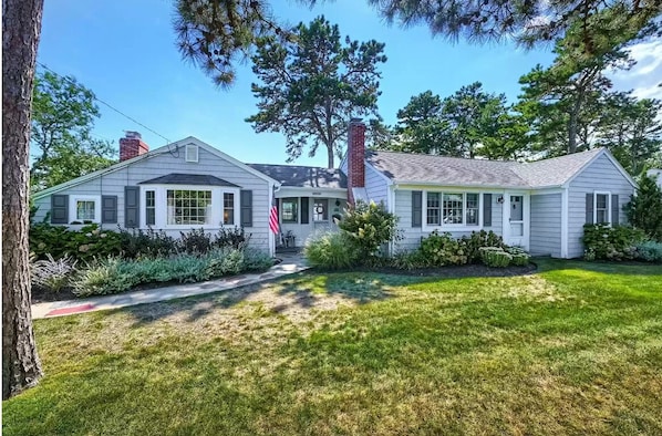 A two-story house with a front porch, a chimney, and a well-maintained lawn.