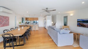 A modern living space with a dining area, kitchen, and a large sofa.