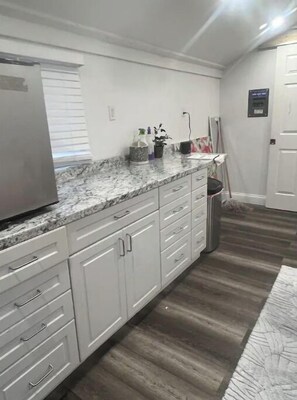 Enjoy cooking in this well-equipped kitchen with a refrigerator, granite countertop, and ample counter space.