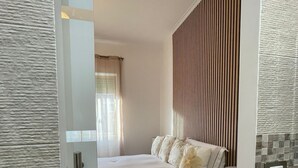 Ein modernes Schlafzimmer mit Bett, Nachttisch und Blick auf den angrenzenden Raum.