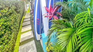 A building with surfboards leaning against it, a pathway, and tropical plants. - Amazing Ocean View Townhouse Condo Elevated Pool & Balcony (Nassau)