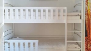 Un lit superposé avec une tête de lit blanche et une petite étagère au-dessus.