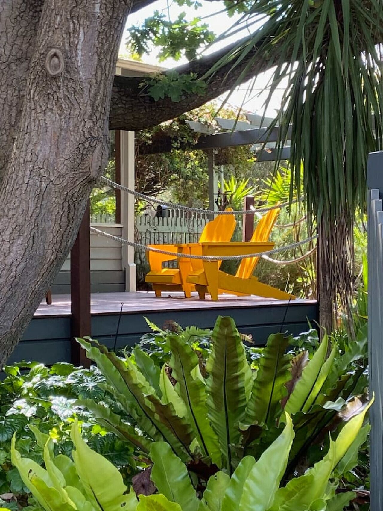 Una sedia amaca sotto una pergola con vista su un giardino e un edificio sullo sfondo.
