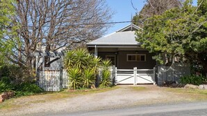 A house with a metal roof, a white fence, and a gate.