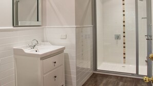 A modern bathroom with a glass-enclosed shower, a white vanity with drawers, and a mirror above the sink.