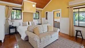 A bedroom with a bed, a sofa, a nightstand, a lamp, and a window with curtains.