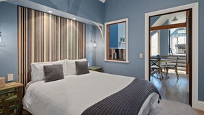 A bedroom with a large bed, a wooden headboard, a mirror, and a view of an outdoor patio.