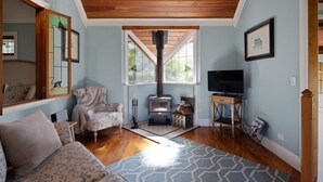 Un salón acogedor con chimenea, un sofá, un televisor y un ventanal grande.