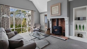 Ein modernes Wohnzimmer mit Kamin, Sofa, Sessel und Glastisch.