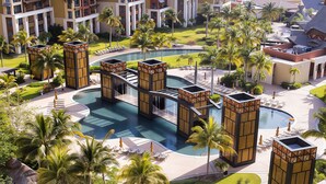 Et resort med flere swimmingpools, palmer og moderne arkitektur.